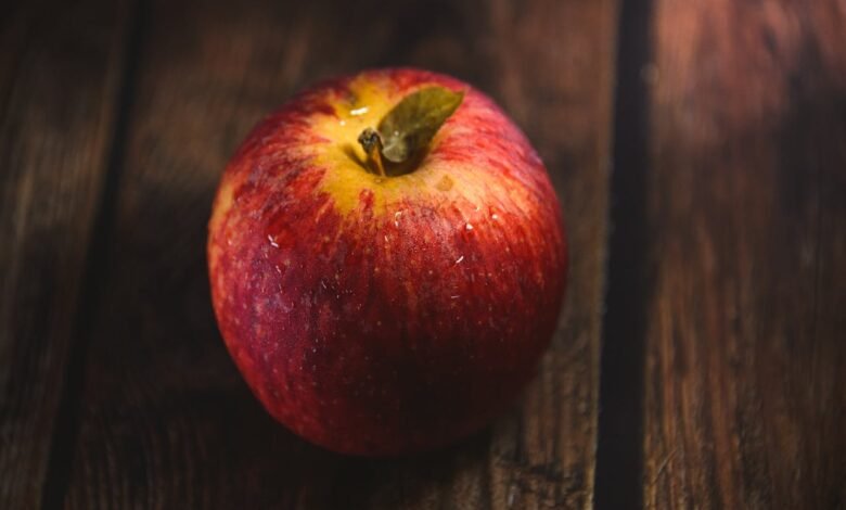 A red apple against a dark wooden backdrop