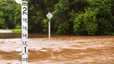 A flooding river with flood level readers depicting the rise level.