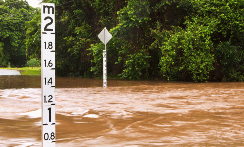 A flooding river with flood level readers depicting the rise level.