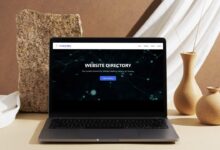Laptop on a table with vase and other ornaments on the table. Laptop screen displays the Sentient Sites homepage